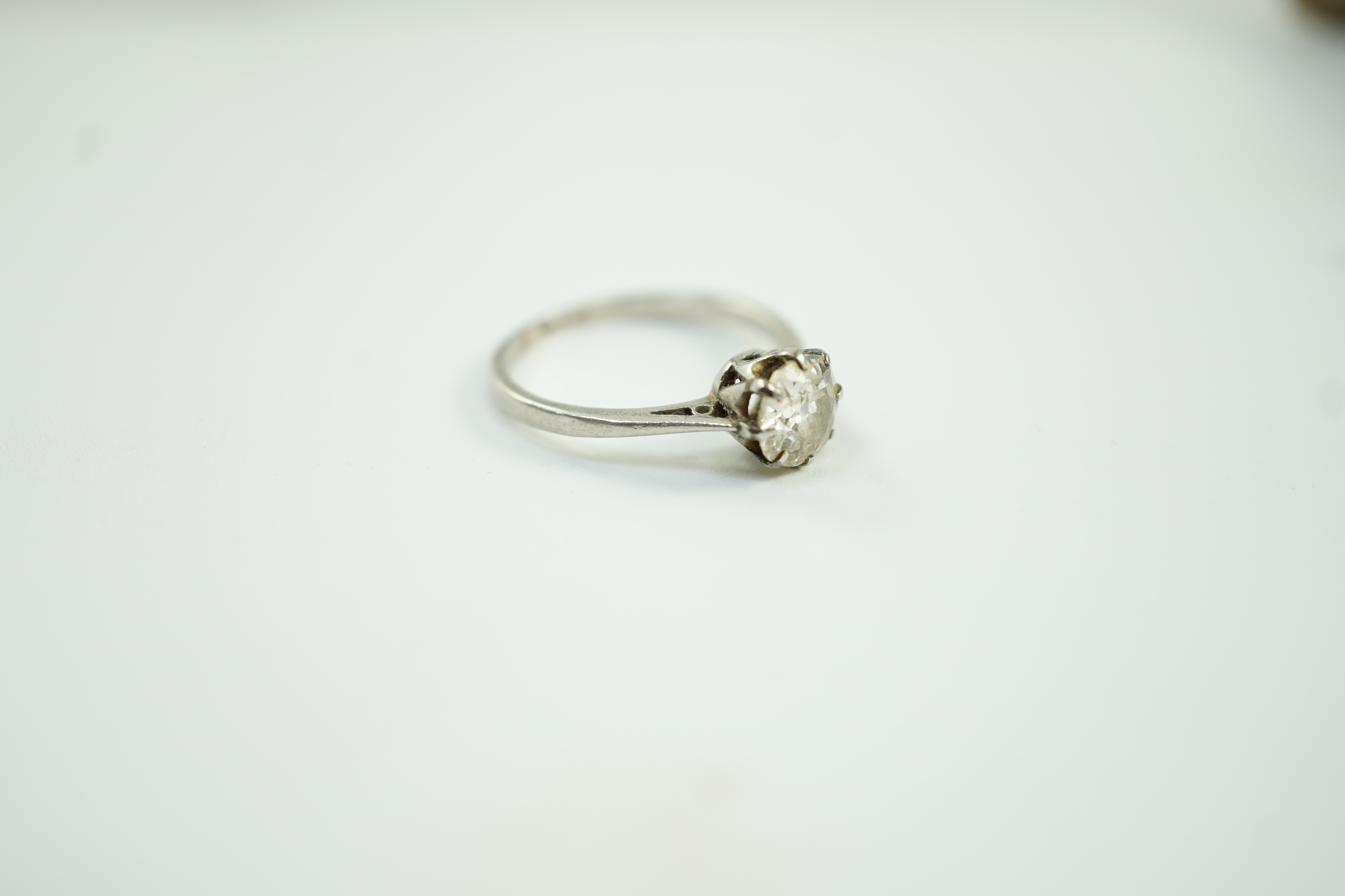 A white metal (stamped plat) and solitaire diamond ring, size J, gross weight 2.6 grams